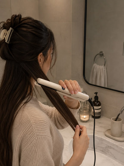 Femme lissant ses cheveux bruns avec le lisseur SILIZIO dans une salle de bain