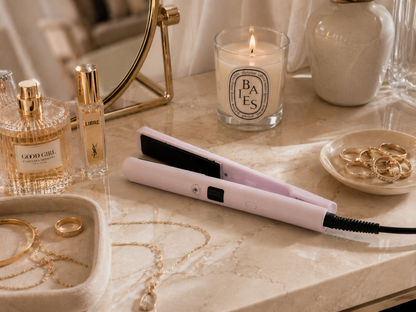 Mini Lisseur SILIZIO rose posé sur une coiffeuse avec bijoux, parfums et bougie